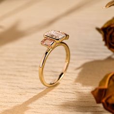 a close up of a ring on a wooden surface with flowers in the back ground