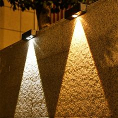 three lights are shining on the side of a building