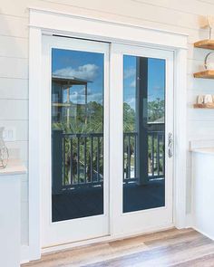 an open sliding glass door in a white room with wood flooring and shelves on the wall