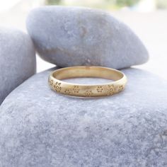 a yellow gold ring sitting on top of a rock