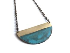 "Brass naturally oxidized with Verdigris patina.  Pendant hangs from an oxidized brass chain. Measurement: 2\" Care: All of our patina pieces are sealed with a resin lacquer to help protect the oxidization, however we do recommend that you keep all patina pieces dry and away from water as it can further the oxidation process and potentially can alter the color.  *Patina is a natural oxidation process so color shades may vary." Patina Jewelry, Shells And Sand, Wake Forest Nc, Rising Tide, Copper Wire Jewelry, Wake Forest, Half Circle, Circle Necklace, Leaf Necklace