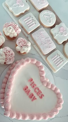 a heart shaped cake next to cupcakes and cookie cutters