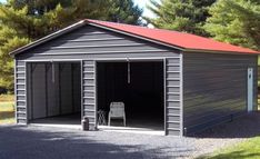 a garage with a red roof and two chairs in the driveway next to some trees