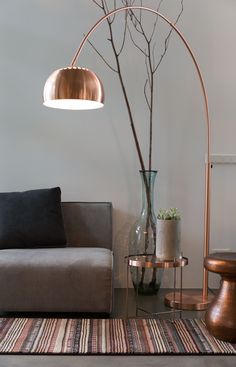 a living room with a couch, lamp and vase on the table in front of it