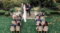 a couple getting married in front of an outdoor wedding ceremony with flowers and greenery