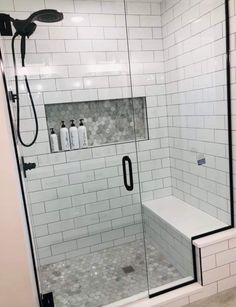 a walk in shower sitting next to a white tiled wall and floor with black trim