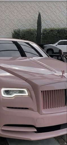 a pink rolls royce parked in front of a building