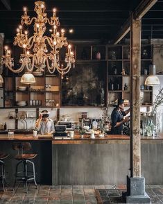 two men working behind the bar in a restaurant with chandelier hanging from the ceiling