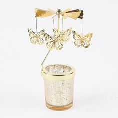 a small pot with some gold butterflies hanging from it's top and two smaller ones in the bottom