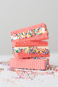 three pink ice cream sandwiches with sprinkles stacked on top of each other