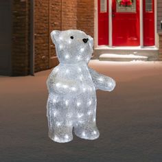 a lighted polar bear standing in front of a red door with lights on it's chest