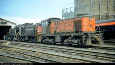 an orange and black train is on the tracks next to some other rail road tracks