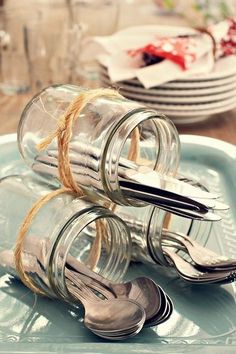 two glass jars with spoons and forks tied to each other on a blue plate