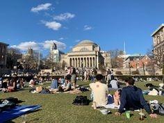 many people are sitting on the grass in front of a building