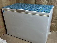 a white refrigerator with blue and green tile on it's top, sitting in a room under construction