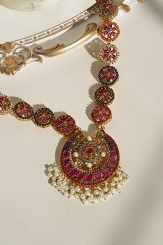 Step into the extravagant fusion of grace and royalty with the "Adiva - Long Mala Necklace Set." This opulent set paints you in luscious shades of multi-color stones and embellishments, elevated by pearl moti hangings. It features a classic embodiment of a beautiful flower motif design that exudes elegant femininity.The set includes a beautifully crafted mala with an adjustable dori for a perfect fit and a pair of dangle earrings, each designed to enhance your regal charm. With an approximate ma Festive Fusion Style Jewelry Sets, Jeweled Round Necklaces For Festivals, Elegant Multicolor Jewelry Sets For Diwali, Traditional Multicolor Ruby Jewelry, Multicolor Jewelry Sets With Intricate Design For Celebration, Multicolor Ruby Jewelry For Festivals, Fusion Style Multicolor Jewelry With Intricate Design, Elegant Multicolor Gemstone Temple Necklace, Multicolor Fusion Necklaces With 17 Jewels