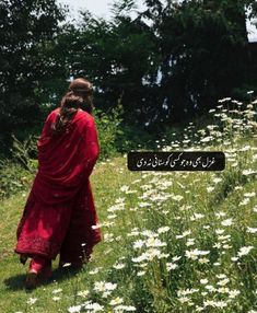 a woman in a red dress is walking through the grass and daisies with an arabic sign