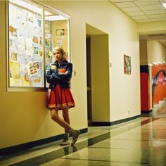 a woman leaning against a wall in a hallway