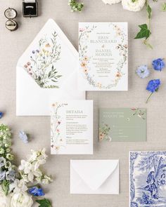 the wedding stationery is laid out with flowers and greenery