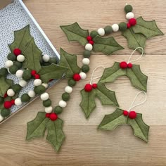 some felt holly decorations on a wooden table