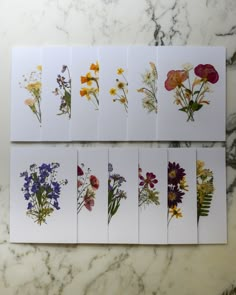 six cards with different flowers on them sitting on a marble counter top next to each other