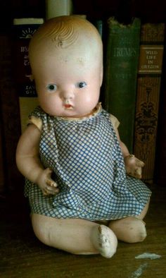 a baby doll sitting on top of a wooden floor next to bookshelves and a book case