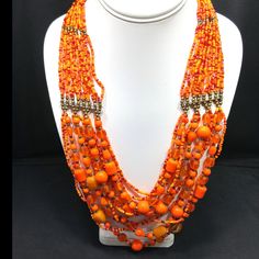 *Description: This vintage 1970's Czech glass seed bead necklace has 16 strands of orange glass beads which move into larger glass beads and connect to 12 strands. It is the perfect Boho necklace from the 1970's. It has two brass toned caps with lobster claw closure. It is in great vintage condition. The length of this necklace is 23 inches for the shortest strand. This would be a great addition to your vintage jewelry collection or make a great vintage gift! *Approximate Measurements: Length - Orange Multi-strand Beaded Necklace With Polished Beads, Orange Multi-strand Polished Beaded Necklaces, Orange Multi-strand Polished Beaded Necklace, Handmade Multi-strand Orange Beaded Necklaces, Vintage Orange Beaded Chain Necklace, Orange Beaded Necklace With Large Round Beads, Vintage Orange Necklace With Colorful Beads, Vintage Orange Beaded Necklace, Traditional Orange Beaded Chain