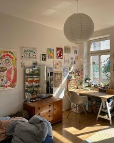 a room filled with lots of clutter and pictures on the wall next to a window