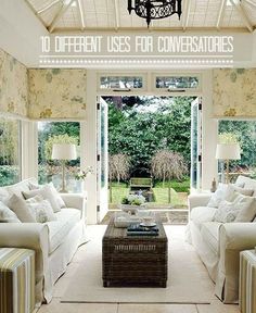 a living room filled with white furniture and lots of windows covered in shades of green