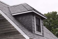 the roof of a house with a shingled dormer and window on it's side