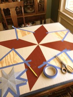 a wooden table with scissors and tape on it, next to a star cutout