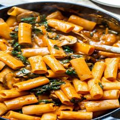 a skillet filled with pasta and spinach