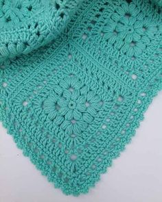 a green crocheted shawl on top of a white table