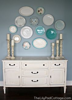 a white dresser sitting next to a wall with plates on it