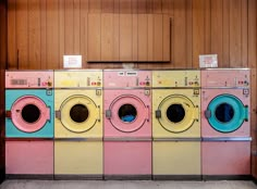 four washers lined up in front of each other with signs above them on the doors