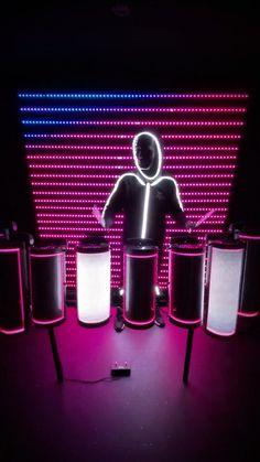 a person standing in front of some speakers with lights on them and a neon wall behind him