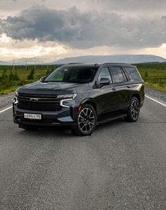 a black suv is parked on the side of the road in front of an overcast sky