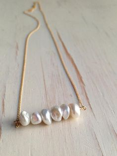 A delicate row of fresh water pearls is wire wrapped onto a 14k gold filled chain.Length is 17 inchesMATERIAL:GOLD-FILLED - 14k Gold filled is considerably durable and considered a lifetime piece of jewelry. This is NOT gold plated or gold dipped vermeil jewelry which can chip off over time with wear. Gold filled metal is essentially a 14k gold tube filled with an inner core metal such as brass and has been mechanically bonded with high very hot heat. It will never chip or flake off such as gold Pearl Bar Necklace, Pearl Birthstone, Fine Silver Jewelry, Gold Bar Necklace, Vermeil Jewelry, June Birthstone, Bijoux Diy, Love Necklace, Gold Filled Jewelry