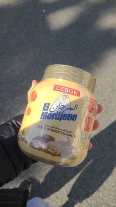 a person holding a jar of food in their hand while wearing gloves on the street