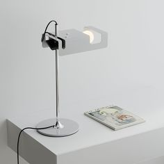 a white table with a book and a lamp on it