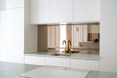 a kitchen with white cabinets and a gold faucet in the middle of it