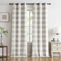 a living room with white curtains and a window in the corner, next to a small table