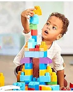 a young boy playing with a large stack of blocks