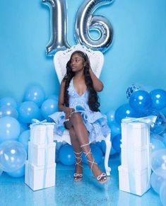 a woman is sitting on a chair in front of balloons and presents for her 16th birthday