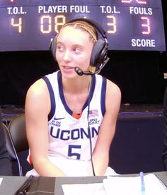 a female basketball player sitting in front of a scoreboard with headphones on her ears