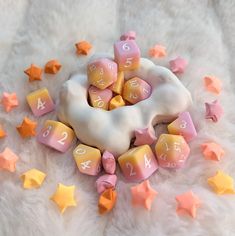 a white bag filled with pink and yellow dice next to star shaped numbers on a fur surface