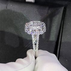 a diamond ring is being held up by someone's hand in a white glove