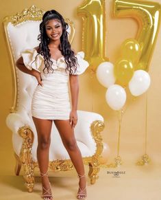 a woman posing in front of balloons and a chair