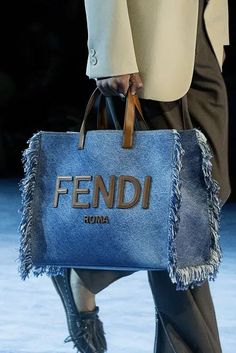 a blue fendi bag is being held by a woman's legs on the runway