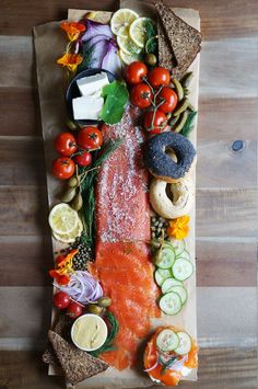 an assortment of food is laid out on a piece of brown paper, including bread, tomatoes, cucumbers, and other vegetables